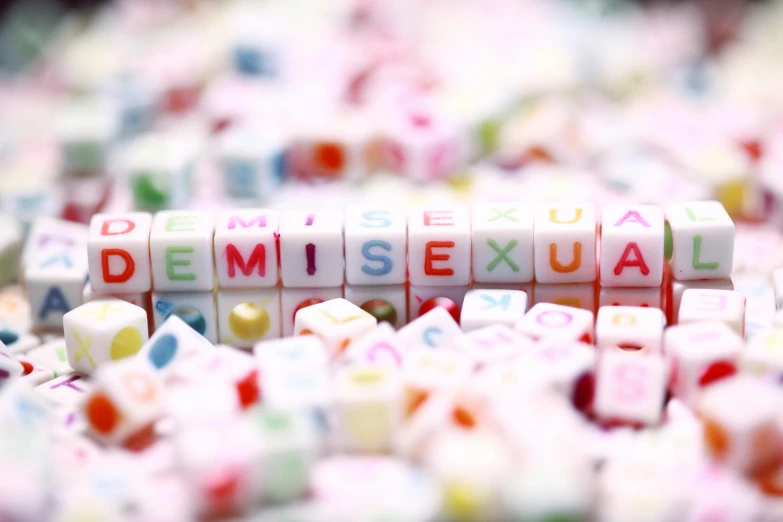 a pile of candies with the word demiise sexual spelled on them, a mosaic, trending on pexels, letterism, cubes on table, queer, microscopic detail, alphabet soup