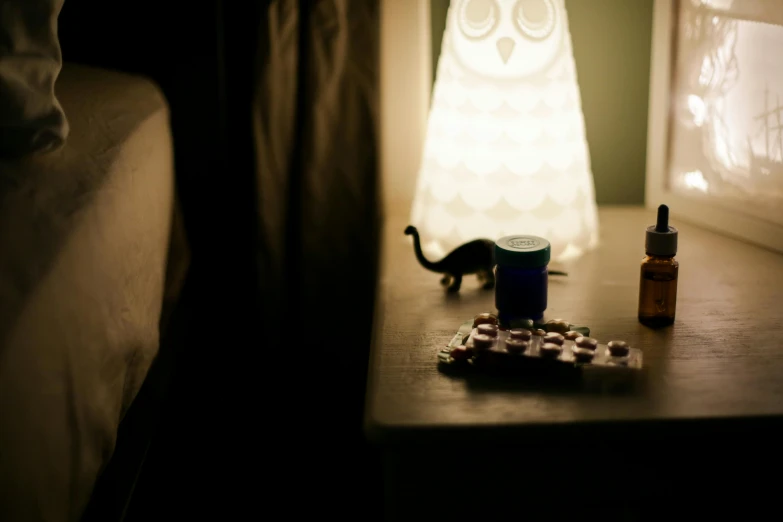 a cat sitting on a table next to a lamp, a still life, unsplash, pills and medicine, dimly lit bedroom, close up photograph, nightime