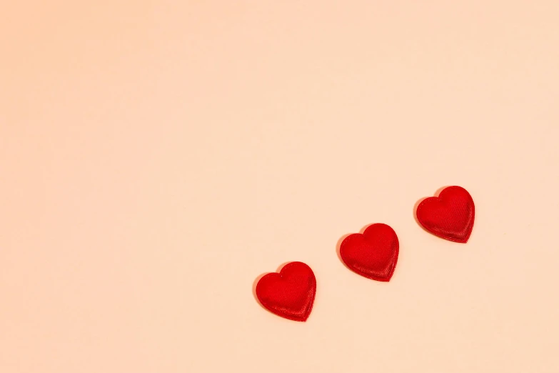 three red hearts on a pink background, an album cover, trending on pexels, minimalism, chocolate, 4 k smooth, trinkets, candy decorations