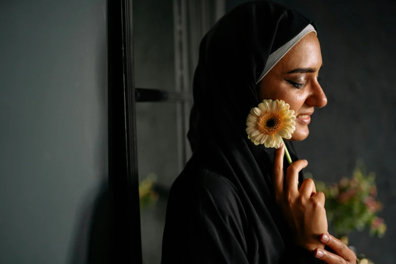 a woman with a flower in her hand, pexels contest winner, hurufiyya, wearing a black robe, profile image, middle eastern skin, reflecting