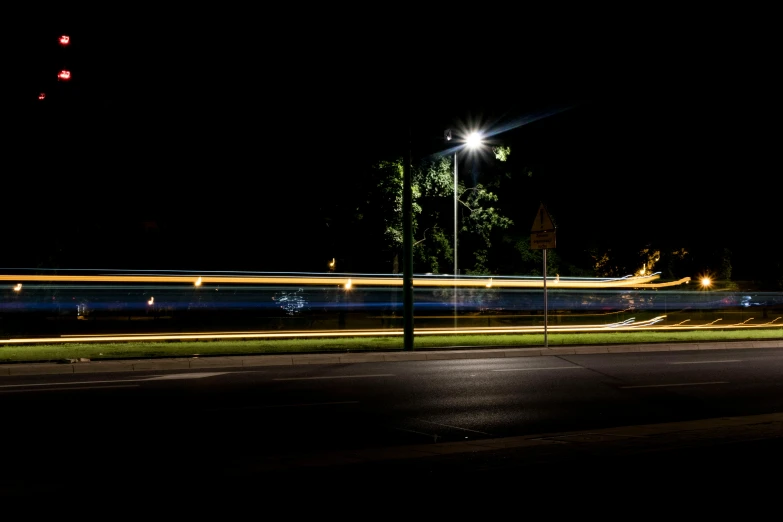 a blurry image of a street at night, by Peter Churcher, unsplash, realism, light trail, bus stop, streetlamp, long exposure
