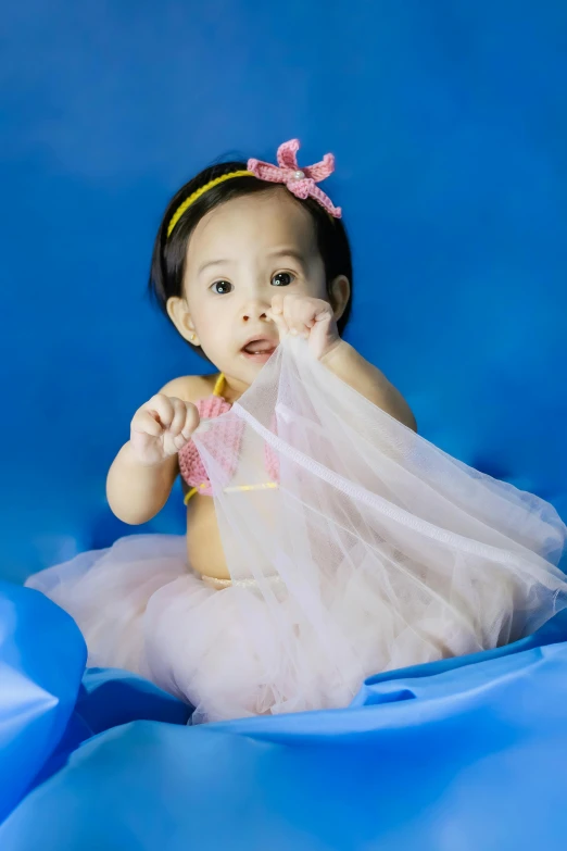 a baby girl in a tutu posing for a picture, a picture, by Basuki Abdullah, shutterstock contest winner, with a blue background, square, softplay, swimming