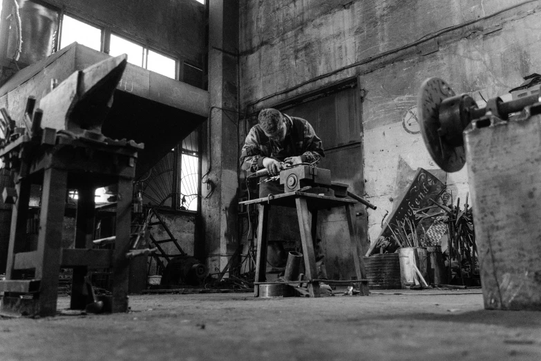 a black and white photo of a man working in a factory, by Carlo Carrà, pexels contest winner, arbeitsrat für kunst, scrap metal on workbenches, a wooden, fan art, prop