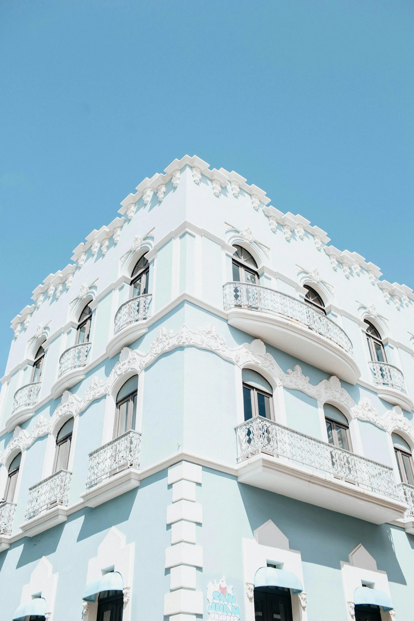 a white building with a blue sky in the background, a colorized photo, unsplash contest winner, neoclassicism, puerto rico, pastel blue, profile image, multiple stories