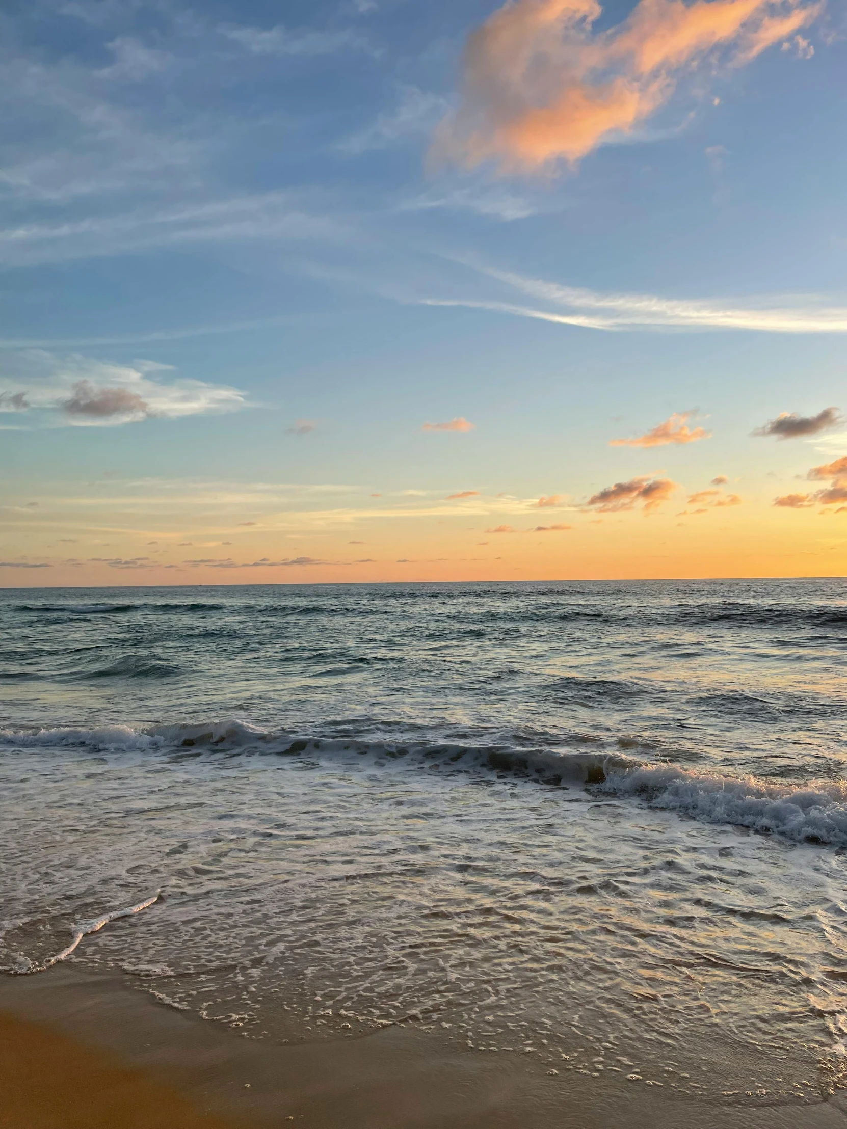 a large body of water sitting on top of a sandy beach, by Robbie Trevino, on the beach during sunset, ocean view, skies, ocean swells