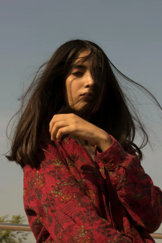 a close up of a person on a skateboard, an album cover, trending on pexels, arabesque, beautiful iranian woman, long hair and red shirt, pale sky, thoughtful pose