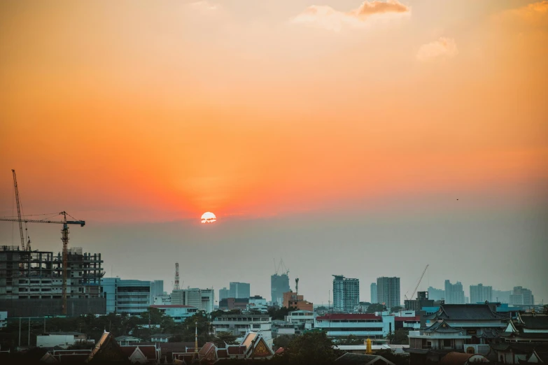 the sun is setting over the city skyline, pexels contest winner, in style of thawan duchanee, from a distance, sunfaded, wide