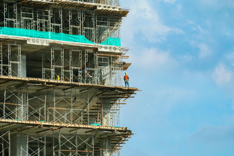 a man standing on top of a scaffolding next to a tall building, by Carey Morris, pexels contest winner, constructivism, bright construction materials, foster and partners, zoomed in, a monumental