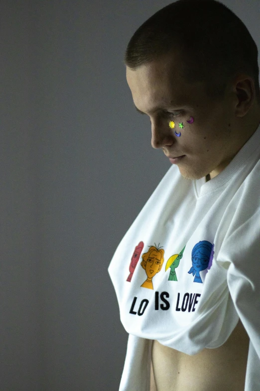 a man in a white shirt with rainbow paint on his chest, inspired by Willem Labeij, graffiti, official store photo, love os begin of all, leonid, he is about 20 years old | short