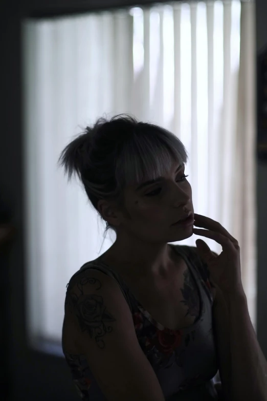 a woman smoking a cigarette in a dark room, inspired by Elsa Bleda, pexels contest winner, realism, girl silver ponytail hair, looking out a window, ( ( theatrical ) ), tattooed