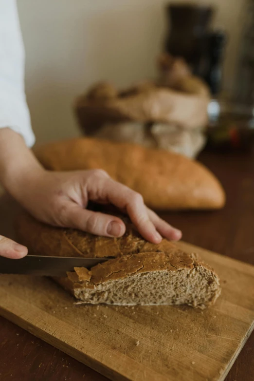 a person cutting a loaf of bread on a cutting board, trending on pexels, renaissance, award - winning crisp details ”, belgium, malt, full-body