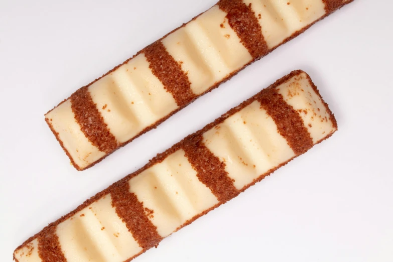 two pieces of cake sitting on top of a white table, a stipple, inspired by Joris van der Haagen, unsplash, art nouveau, cell bars, lined up horizontally, ermine, high angle close up shot