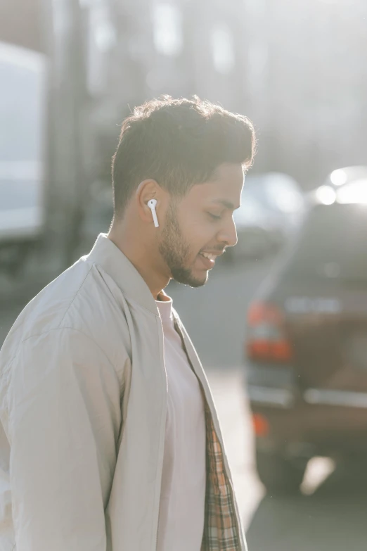 a man standing on the side of the road with a cell phone in his hand, an album cover, trending on pexels, renaissance, earbuds jewelry, airpods, side view profile centered, australian