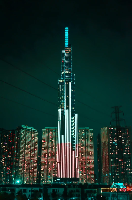 a tall building in the middle of a city at night, an album cover, inspired by Beeple, pexels contest winner, pixel art, teal electricity, taken in the early 2020s, telephoto shot, towering