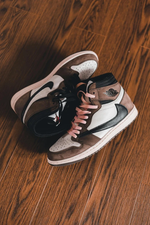 a pair of sneakers sitting on top of a wooden floor, a picture, inspired by Jordan Grimmer, unsplash, renaissance, brown and pink color scheme, air jordan 1 high, ( ( brown skin ) ), instagram post
