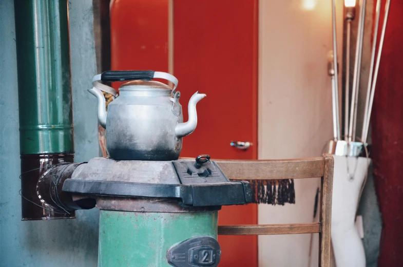 a stove with a tea pot on top of it, by Daniel Lieske, trending on unsplash, mingei, quirky shops, background image, molten metal house, in style of lam manh