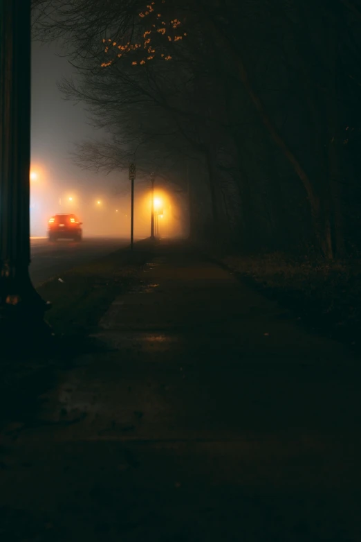 a street light sitting on the side of a road, by Andrew Domachowski, pexels contest winner, gothic fog ambience, orange fog, headlights, scary night