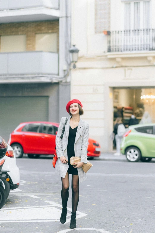 a woman standing in the middle of a street, trending on pexels, wearing a french beret, red and grey only, barcelona, happy fashion model