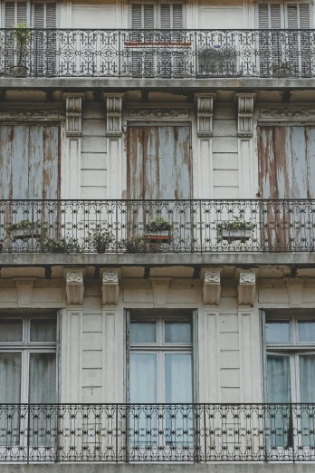 a tall building with lots of windows and balconies, unsplash, art nouveau, rustic and weathered, french door window, deteriorated, planters