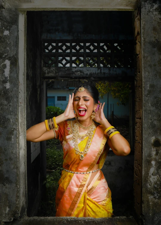 a woman in a yellow and orange sari, an album cover, inspired by Raja Ravi Varma, pexels contest winner, laughter and screaming face, color photograph portrait 4k, wedding, square