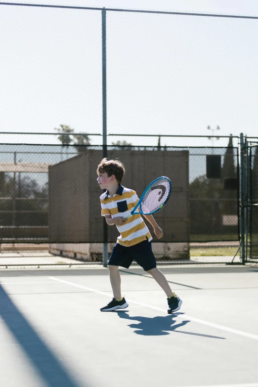 a young man holding a tennis racquet on a tennis court, unsplash, happening, kids, full length shot, gold, teenage boy