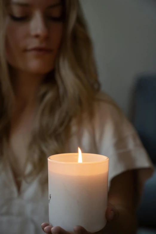 a woman holding a lit candle in her hands, profile image