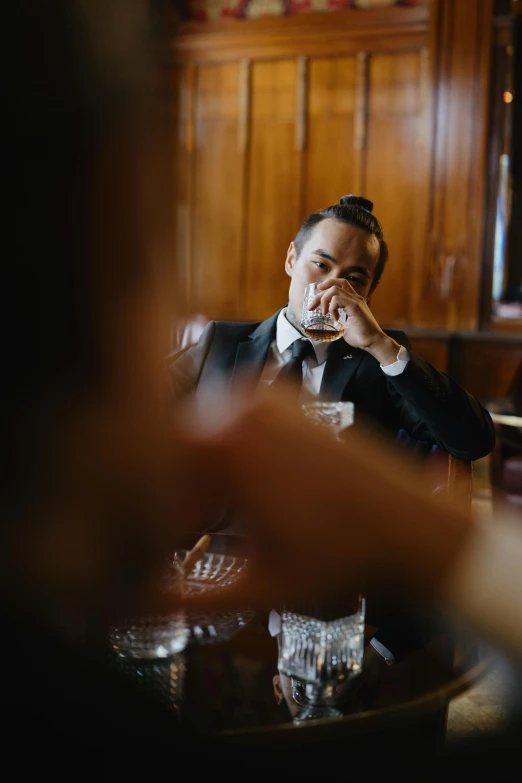a man in a suit sitting at a table, inspired by William Grant Stevenson, trending on unsplash, renaissance, drinking and smoking, joe taslim, groom, emotional face shot