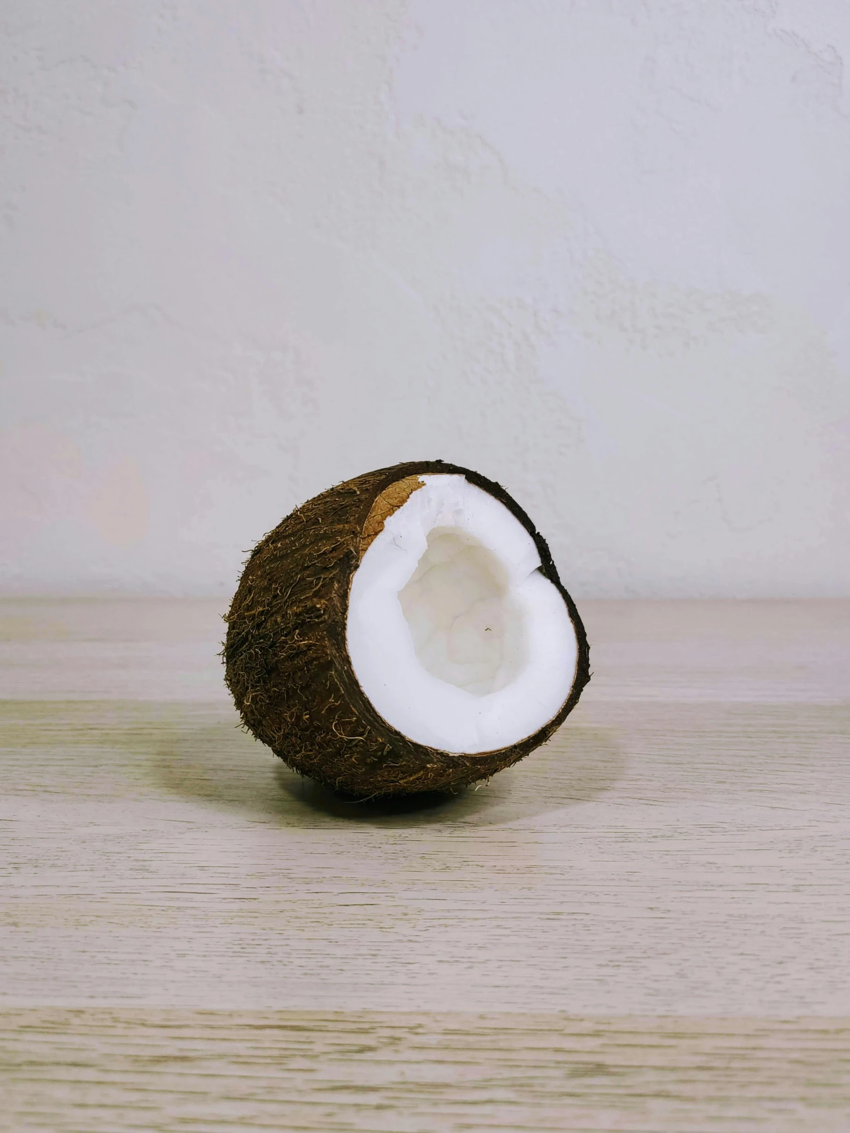 a coconut sitting on top of a wooden table, by Robbie Trevino, textured base ; product photos, close-up product photo, curated collection, smol