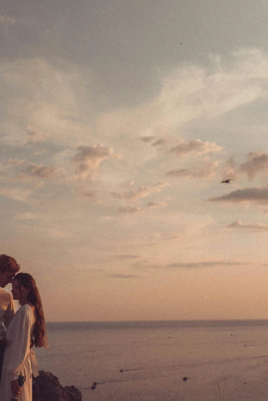 a man and a woman standing next to each other on a beach, a picture, pexels contest winner, romanticism, sunfaded, skies behind, ( ( theatrical ) ), music video