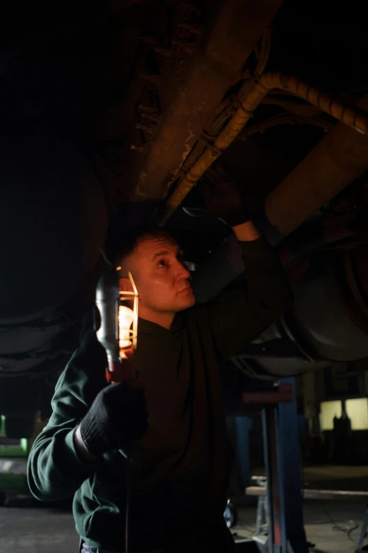 a man that is standing under a car, holding a torch, mechanics, sean mcloughlin, maintenance photo