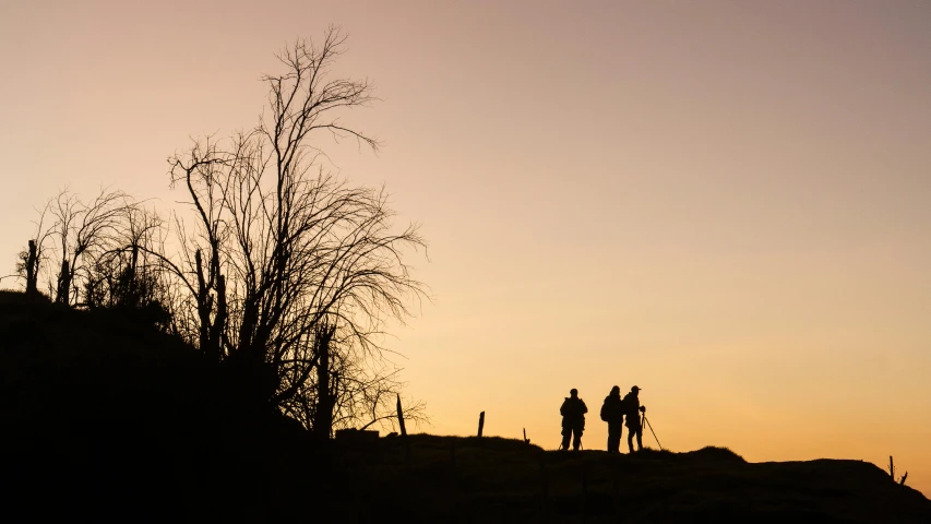 a couple of people standing on top of a hill, by Peter Churcher, pexels contest winner, backlight glow, hunting, walking to the right, shot on 1 5 0 mm