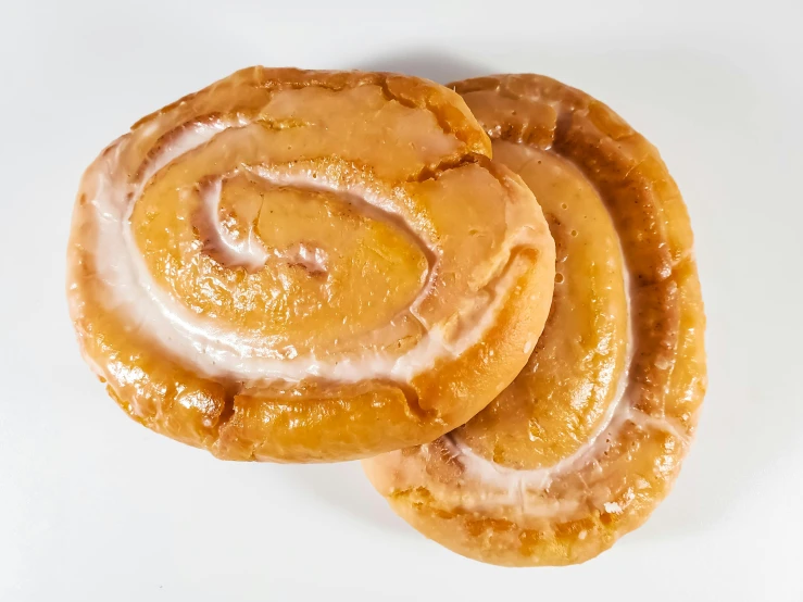 a close up of two pastries on a white surface, sprial, detailed product image, glazed, fan favorite