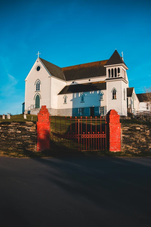 a church sitting on the side of a road, on the coast, red fluid on walls of the church, taken at golden hour, conor walton