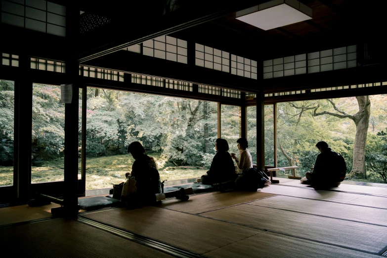 a group of people sitting on top of a wooden floor, inspired by Sesshū Tōyō, trending on unsplash, sōsaku hanga, beautiful surroundings, 2000s photo, japanese architecture, tea ceremony scene