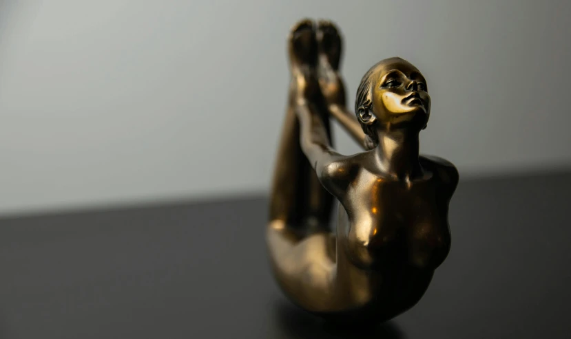a close up of a statue on a table, a bronze sculpture, inspired by Hedi Xandt, pexels contest winner, marjaryasana and bitilasana, woamn is curved, brass plated, pinup body