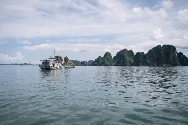 a boat floating on top of a large body of water, by Rachel Reckitt, unsplash contest winner, vietnam, fan favorite, limestone, subtitles