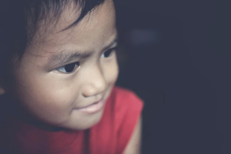 a close up of a child with a cell phone, pexels contest winner, hurufiyya, south east asian with round face, his eyes glowing red, looking her shoulder, desaturated