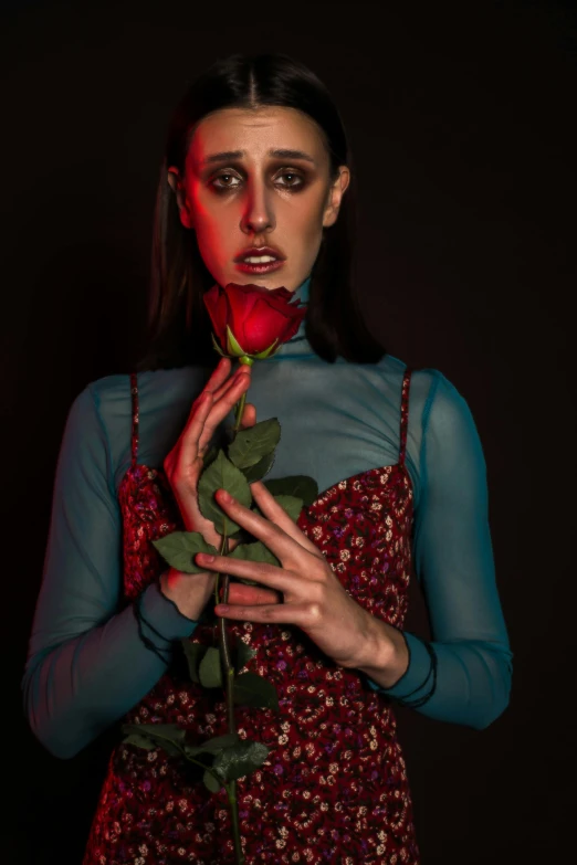 a woman in a red dress holding a rose, an album cover, inspired by Ignacy Witkiewicz, aestheticism, blue rose, non binary model, ((portrait)), concerned expression