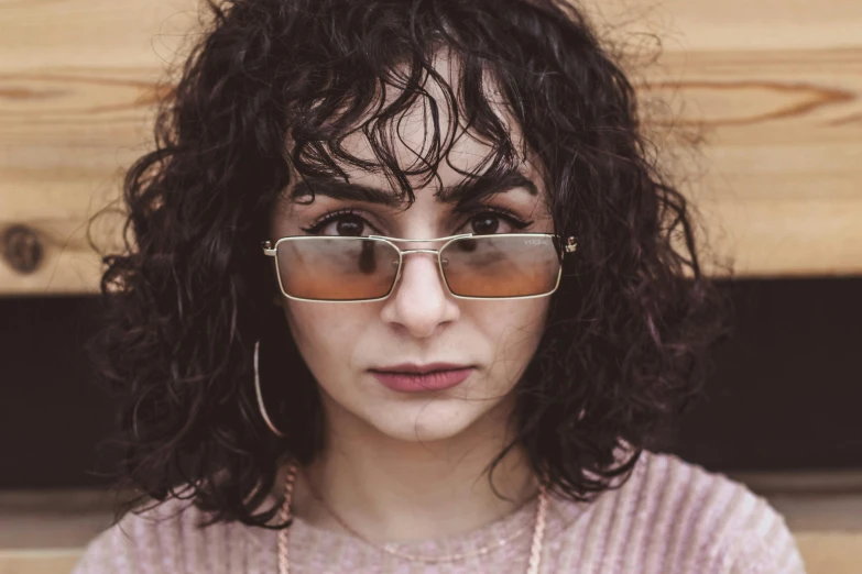 a close up of a person wearing sunglasses, inspired by Elsa Bleda, trending on pexels, photorealism, curly bangs, serious look, young middle eastern woman, square face