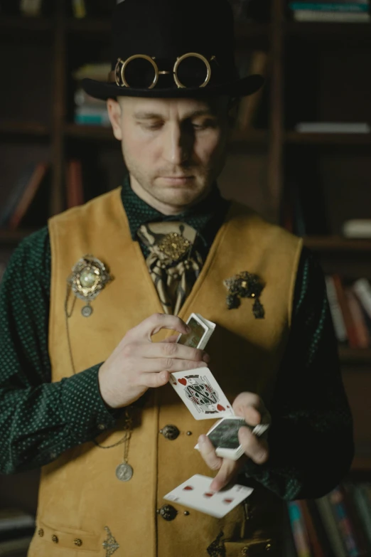 a man in a top hat and vest holding playing cards, a portrait, unsplash, color footage, full color still, apothecary, video still