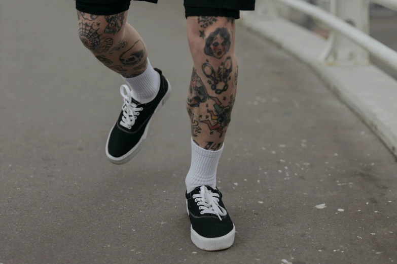 a close up of a person with tattoos on their legs, inspired by Seb McKinnon, pexels contest winner, wearing white sneakers, wearing black shorts, street clothing, vanta black