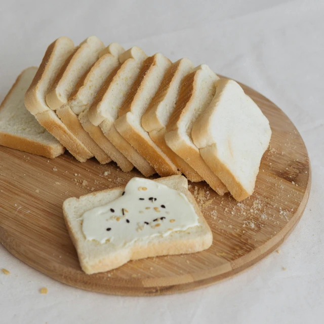 a wooden cutting board topped with slices of bread, mingei, white with black spots, japanese collection product, yeast, lumi