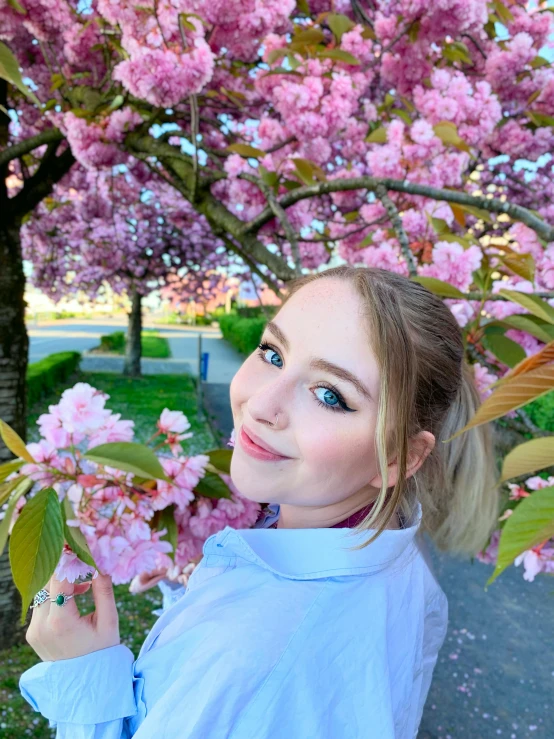 a woman standing in front of a tree with pink flowers, reddit, happening, 2 5 6 x 2 5 6 pixels, 🎀 🧟 🍓 🧚, portait photo profile picture, nina tryggvadottir