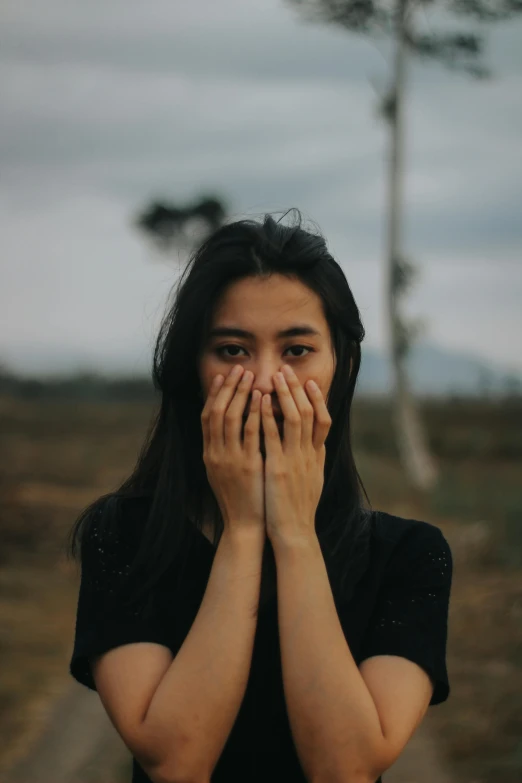 a woman covering her face with her hands, pexels contest winner, asian face, long open black mouth, landscape shot, flirting