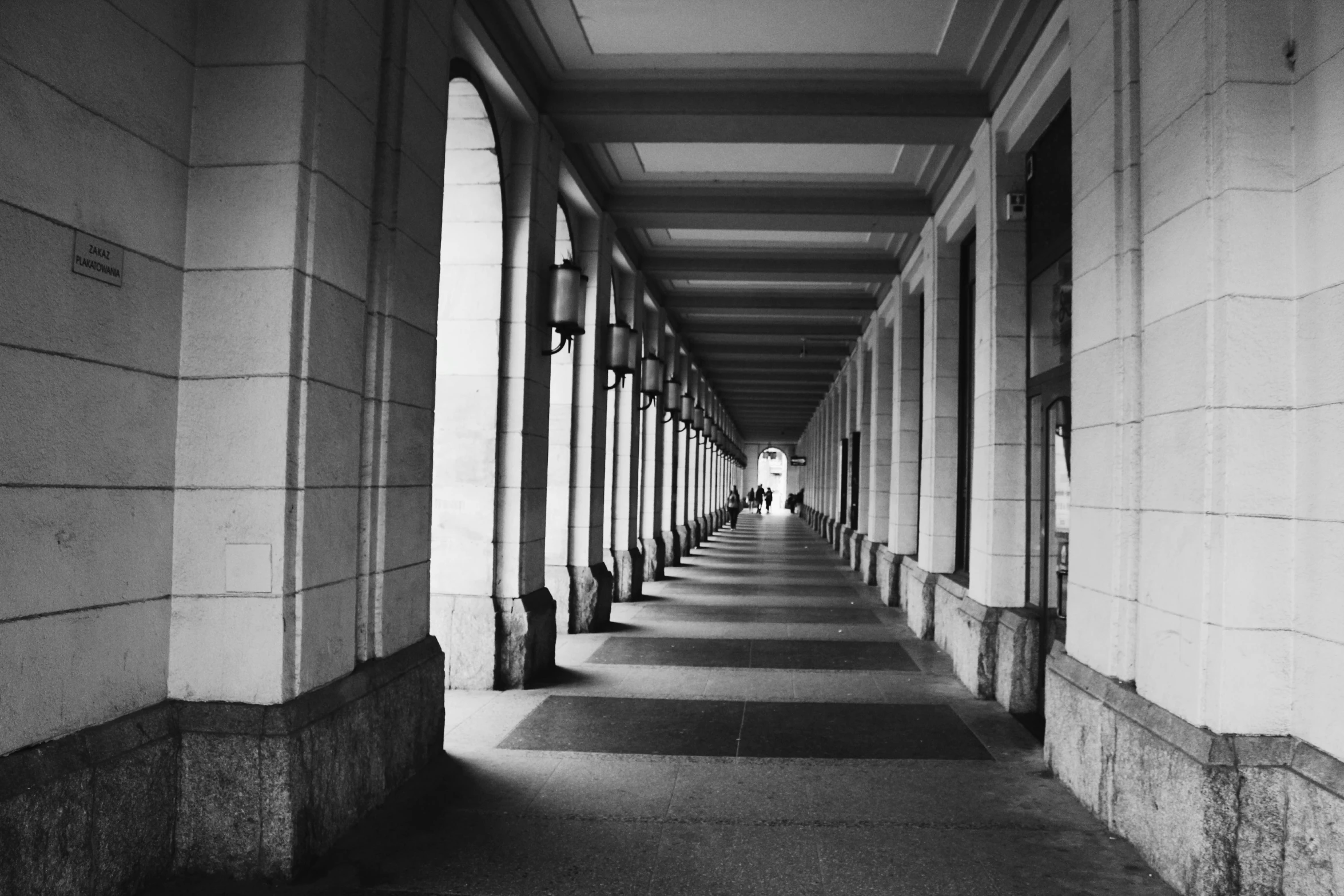 a black and white photo of a long hallway, inspired by Pierre Pellegrini, unsplash, colonnade, photo taken on fujifilm superia, munich, singapore esplanade