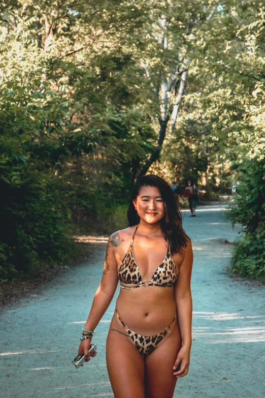 a woman in a bikini walking down a dirt road, asian descent, slightly smiling, in woods, 2019 trending photo