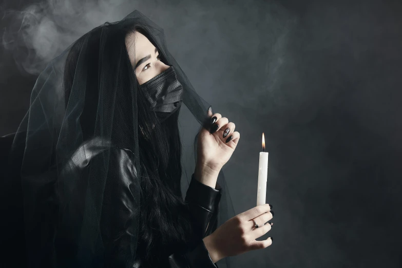 a woman in a black veil holding a candle, an album cover, inspired by Elsa Bleda, trending on pexels, gothic art, smoker, white man with black fabric mask, techwear occultist, on a gray background