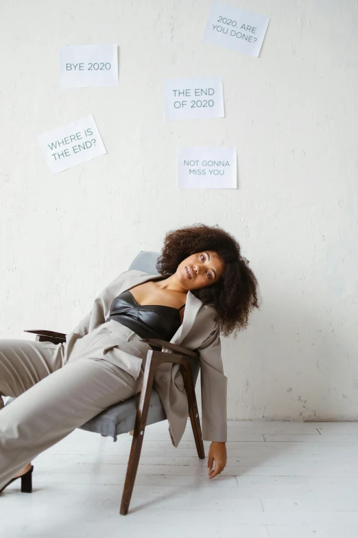 a woman that is laying down on a chair, trending on pexels, renaissance, grey suit, with afro, positive mood, brainstorm