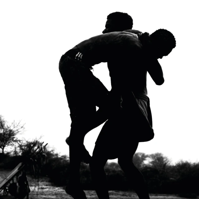 a couple of men standing on top of a skateboard, boxing, silhouettes in field behind, kano), wrestling