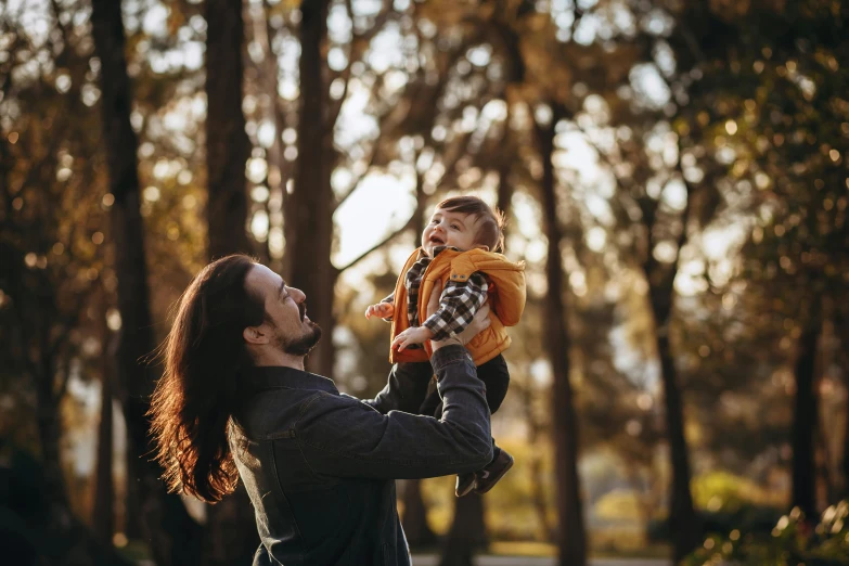 a man holding a small child up in the air, pexels contest winner, enjoying a stroll in the forest, avatar image, australian, hair